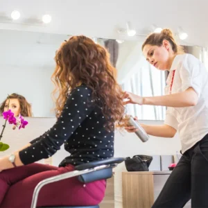 Happy Young Woman With Hairdresser at Hair Salon